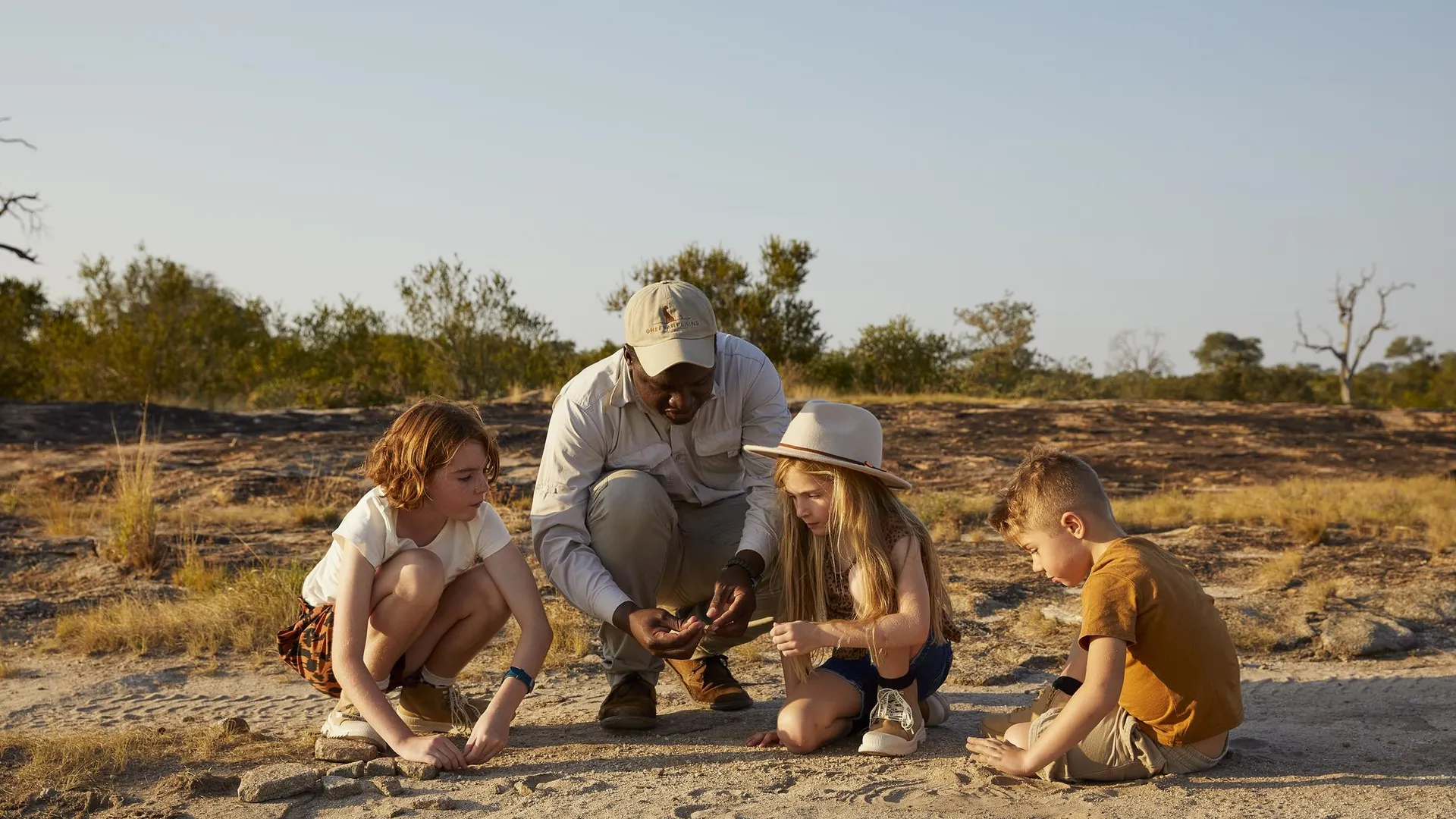 Niños descubriendo huellas con su guía en un safari familiar en Sudáfrica
